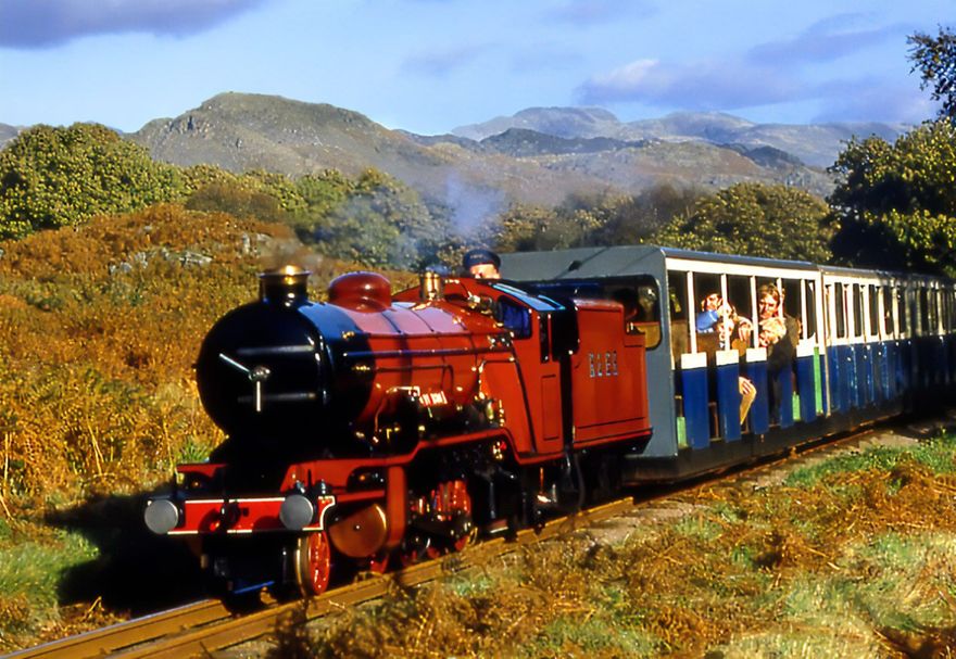 The Ravenglass & Eskdale Railway is one of the oldest and longest narrow gauge railways in England, known affectionately as La’al Ratty meaning “little railway“ in olde Cumbrian dialect. It was 105 years ago in April 1913 that the original 3ft line closed and in 1915 the new 15in La’al Ratty was born. Our heritage steam engines transport passengers from Ravenglass, the only coastal village located in two UNESCO World Heritage Sites, the Lake District National Park and Frontiers of the Roman Empire Hadrians Wall, to Dalegarth for Boot some 210ft above sea level.   The line is seven miles long with a journey time of 40 minutes each way offering spectacular views over the estuaries and countryside with England’s highest mountains in the distance. There are great walks between and from the seven intermediate request stops Our cosy covered , half open and open top carriages provide the best of comfort and views as you travel up the line